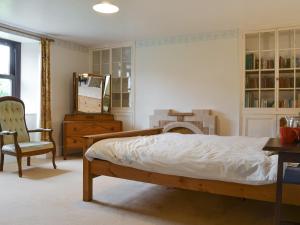 a bedroom with a bed and a chair and a mirror at Tutchenor Farmhouse in Beaworthy