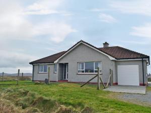 a house with a garage on a grass field at Bute Cottage in Daliburgh