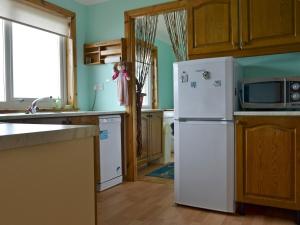 La cuisine est équipée d'un réfrigérateur blanc et d'un four micro-ondes. dans l'établissement Bute Cottage, à Daliburgh