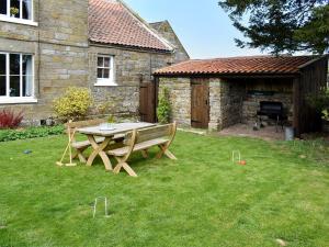 a wooden table and bench in a yard at Tillys Cottage in Goathland