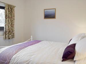 a white bed in a bedroom with a picture on the wall at Sea Breeze in The Mumbles