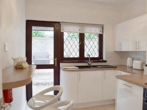 a kitchen with white cabinets and a sink at Sea Breeze in The Mumbles