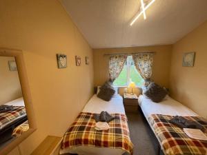 タターズホールにあるLuxury Lakeside Lodge L1 with hot tub situated at Tattershall Lakes Country Parkの窓のある小さな部屋にベッドが2つある +24枚の写真