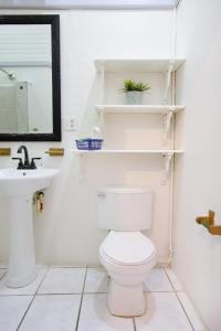 a bathroom with a toilet and a sink and a mirror at Sea Eye Hotel - Sunset Building in Utila