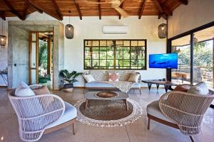 ein Wohnzimmer mit Sofa, Sesseln und Fernseher in der Unterkunft SELVA RESORT Ocean View Luxury Villas in Playa Santa Teresa