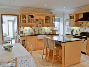uma cozinha com armários de madeira e uma mesa com cadeiras em Meadowsweet em Newburgh