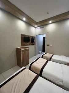 a bedroom with two beds and a tv on the wall at اوتاد الششة in Mecca