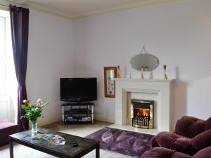 a living room with a fireplace and a tv at Bonshawside Farmhouse in Kirtlebridge