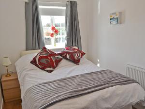 a bed with two pillows on it with a window at The Snug in Valley