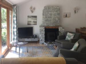 een woonkamer met een stenen open haard en een televisie bij Oaktree Cottage in Appledore