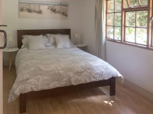 een slaapkamer met een bed met een wit dekbed en 2 ramen bij Oaktree Cottage in Appledore