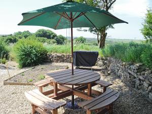 a picnic table with a green umbrella and a chair at Dover Row Cottage in Zelah