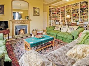 a living room with green couches and a fireplace at Lochside Garden House - S4484 in Town Yetholm