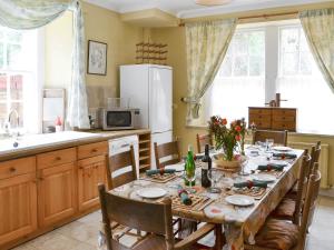 a kitchen with a table with chairs and a tableablish at Lochside Garden House - S4484 in Town Yetholm