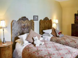 a bedroom with two beds with teddy bears on the bed at Lochside Garden House - S4484 in Town Yetholm