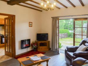 a living room with a couch and a tv at Beudy Mawr - 16985 in Brynsiencyn