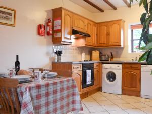 una cocina con armarios de madera y una mesa con lavavajillas en Beudy Mawr - 16985, en Brynsiencyn