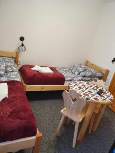 a room with two beds and a table and a chair at Przy Tartaku in Jurgów