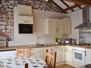 a kitchen with white cabinets and a table with chairs at Fulmar Cottage in Flamborough