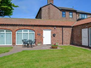 a brick house with tables and chairs in a yard at Fulmar Cottage in Flamborough