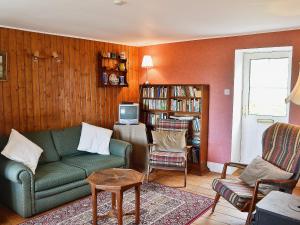 sala de estar con sofá verde y TV en Rosscot, en Ankerville