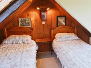 two beds in a room with wooden walls at Rosscot in Ankerville