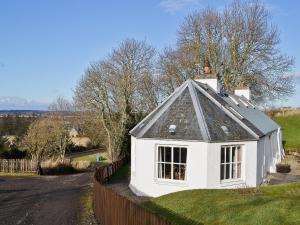 una pequeña casa blanca con techo negro en Rosscot, en Ankerville