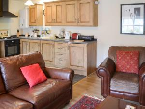 uma cozinha com duas cadeiras de couro e um sofá em Broomstick Cottage em Elsdon