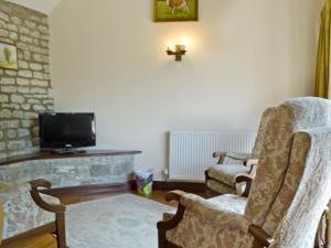 ein Wohnzimmer mit 2 Stühlen und einem TV in der Unterkunft Daisy Cottage in Chipping Sodbury