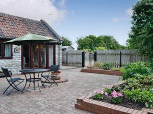 eine Terrasse mit einem Tisch, Stühlen und einem Sonnenschirm in der Unterkunft Daisy Cottage in Chipping Sodbury