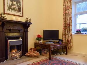 a living room with a television and a fireplace at Apple Cottage in Forgandenny