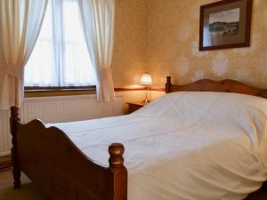 a bedroom with a large white bed with a window at Tyrella in Shebbear