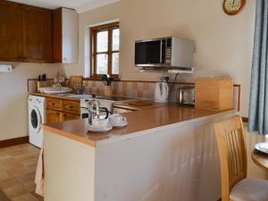 a kitchen with a counter top and a microwave at Tyrella in Shebbear