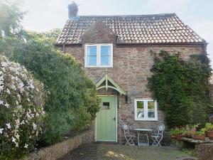 a brick house with a green door and a table at Hollies Cottage in Draycott