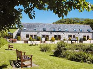 a large stone building with benches in a yard at Bergerac Cottage in Uplyme