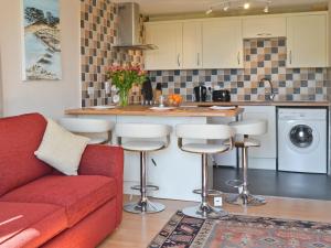a living room with a red couch and a kitchen at Garden View in Brixham