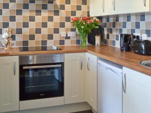 una cocina con armarios blancos y un jarrón de flores en Garden View en Brixham