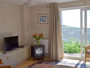 a living room with a television and a window at Garden View in Brixham