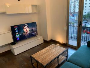 ein Wohnzimmer mit einem Flachbild-TV und einem Tisch in der Unterkunft Apartamento valencia centro in Valencia
