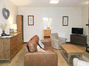 a living room with a leather couch and a table at The Cottage in Stocksfield