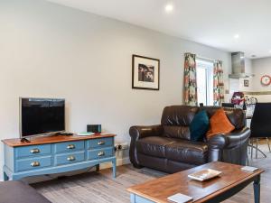 a living room with a leather couch and a tv at Downdinner Hill in Whitby