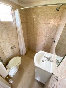 a bathroom with a white toilet and a sink at Cabañas Giramundos in Punta Del Diablo