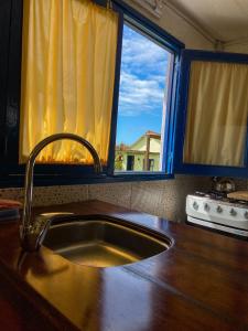 una cocina con fregadero y ventana en Cabañas Giramundos en Punta del Diablo