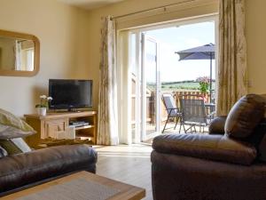 a living room with a couch and a television and a balcony at Hazel Cottage in Shotton