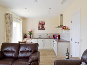 a living room with a couch and a kitchen at Hazel Cottage in Shotton