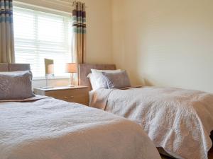 a bedroom with two beds and a window and a table at Hazel Cottage in Shotton