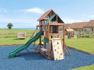 a playground with a slide and a play structure at Lodge Farmhouse in Scarborough
