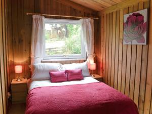 a bedroom with a large bed with a window at Cedar Lodge in Palnackie