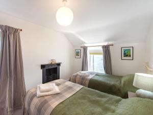 two beds in a room with a fireplace at Blue Sails-jpv in Llangoed
