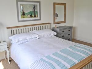 a bedroom with a large white bed and a dresser at Morys Cottage in Keiss